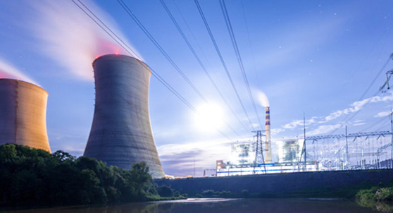 cooling towers at a nuclear power generation plant with nearby transmission lines