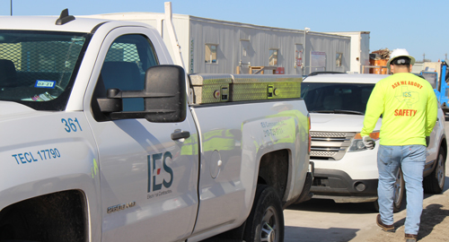 a construction technician in hard hat and safety shirt walking past construction vehicles