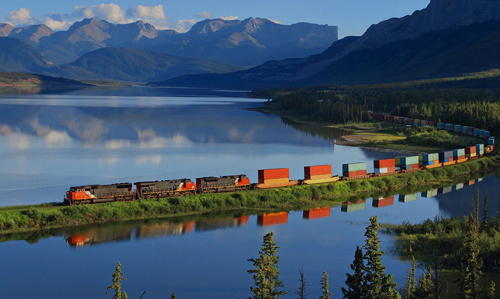3 diesel locomotives pulling a long freight train near the Rocky Mountains 